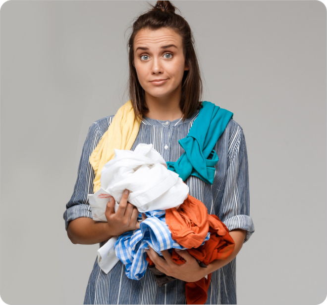 Eine Frau mit einem Haufen zerknüllter Wäsche in der Hand.